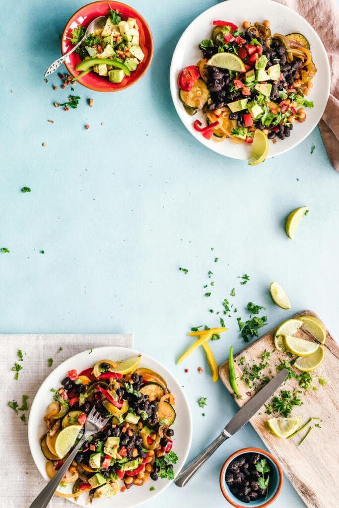 pexels-photo-1640774-1640774 Colorful Mexican salad with avocado, black beans, and lime on a light blue surface.